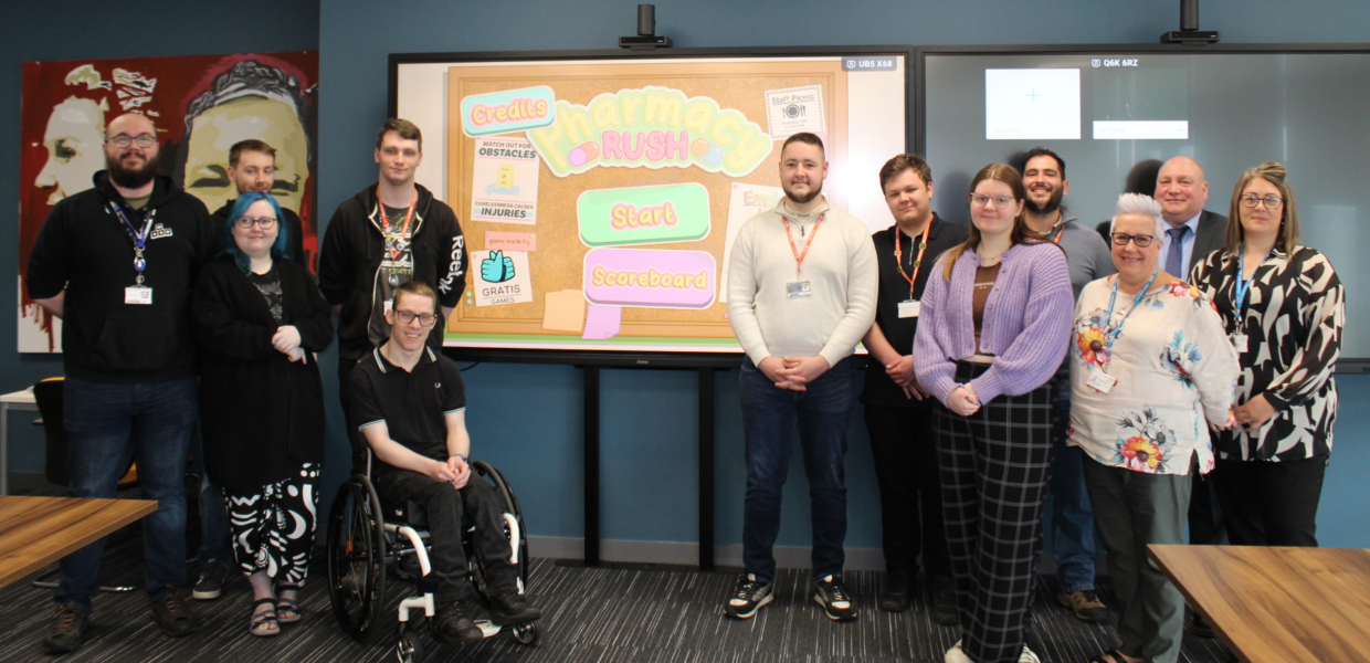 NHS staff and students/staff from The Grimsby Institute pictured in front of a screen showing a video game