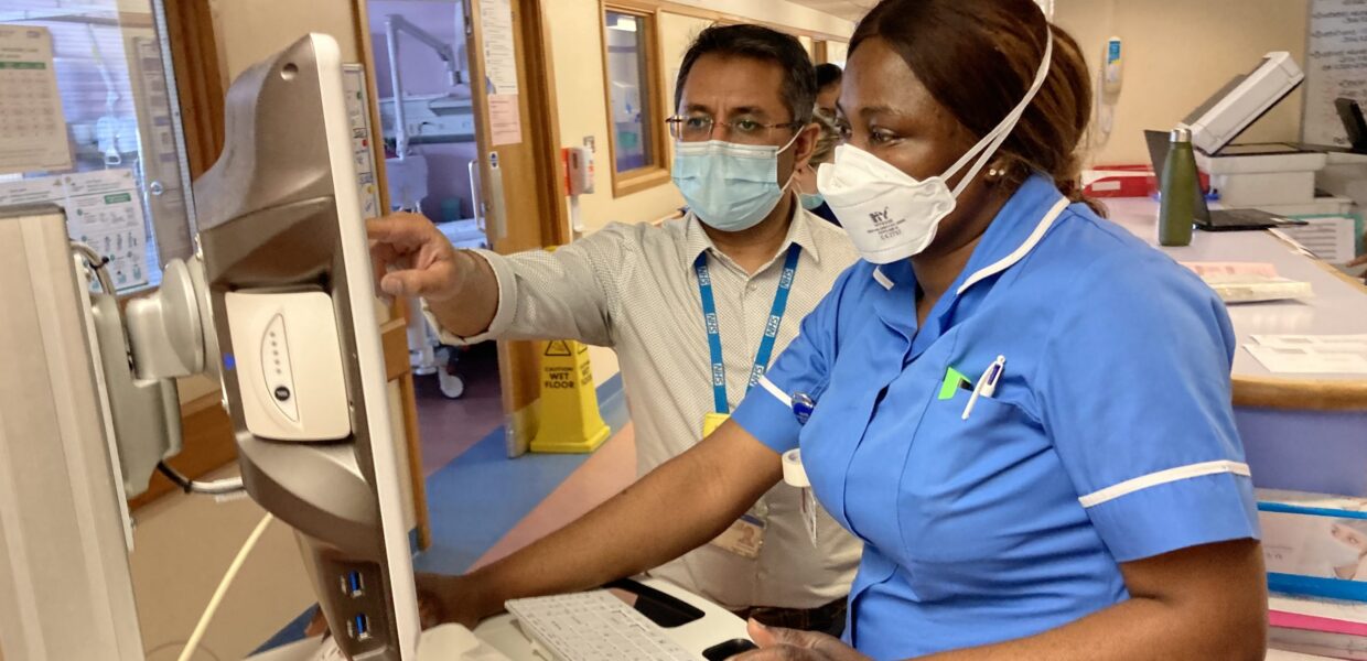 A nurse and doctor looking at a screen on a ward