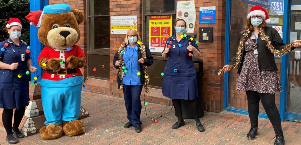 Hospital staff holding Christmas decorations next to Scrubs the bear