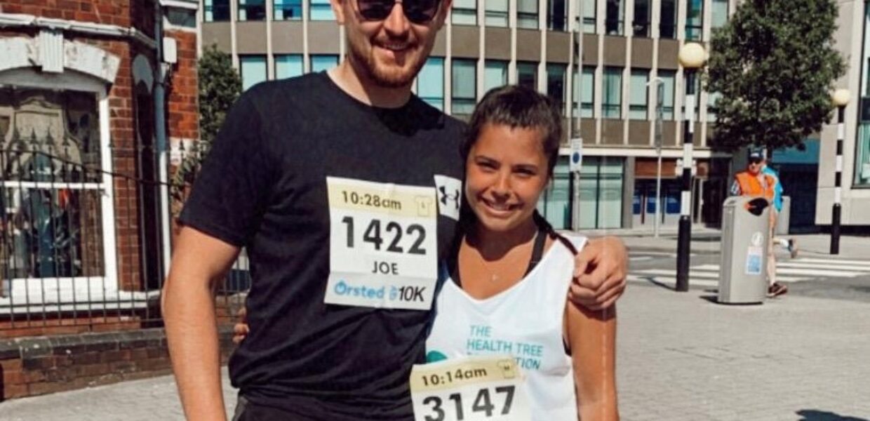 A man and a woman stood outside wearing running gear.