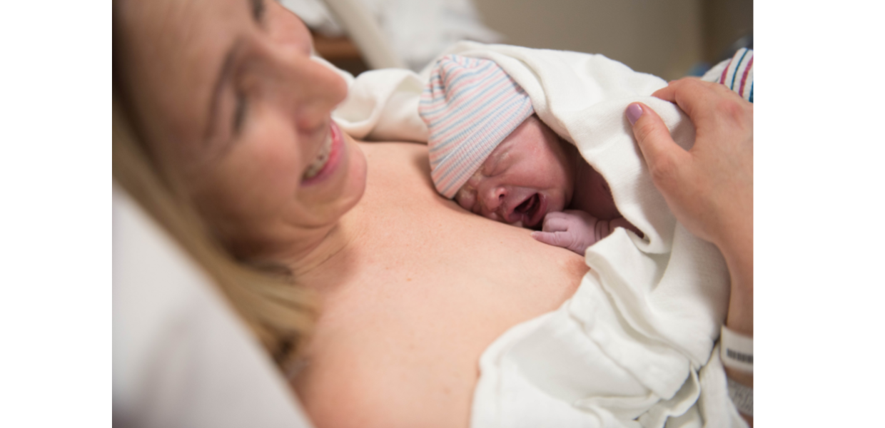 A woman lying on a bed holding a new born baby