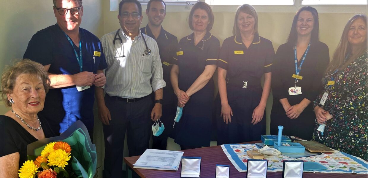 Staff pictured with a patient holding flowers. Medals are on the table.