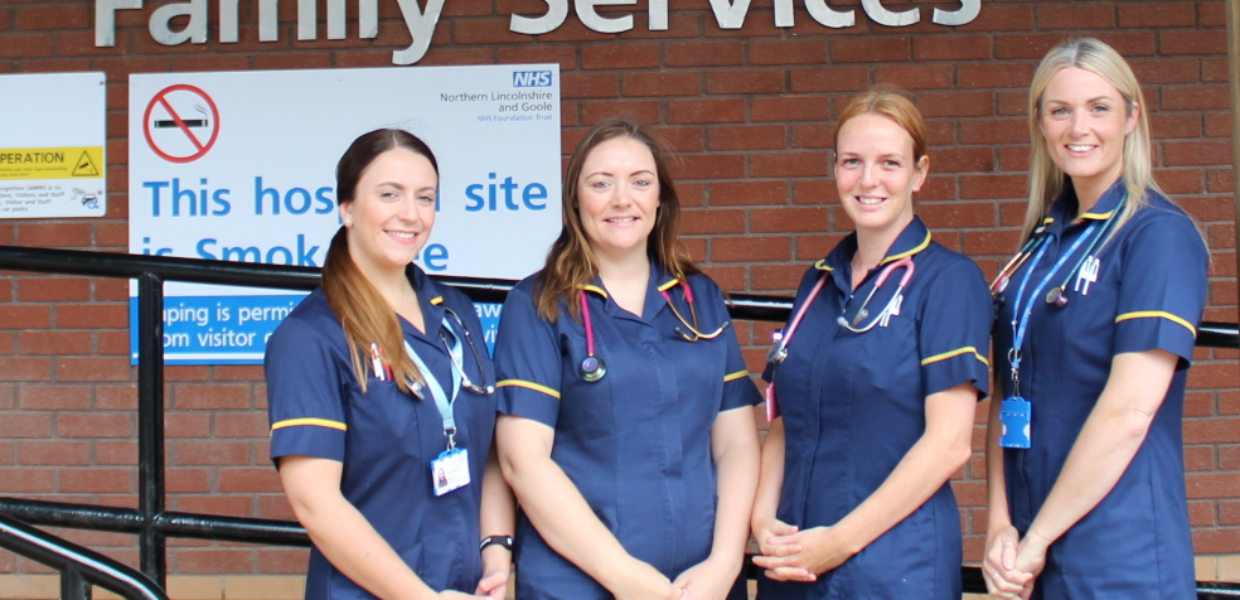 Four nurses in uniform stood outside a sign saying 'Welcome to department of Family Services'.