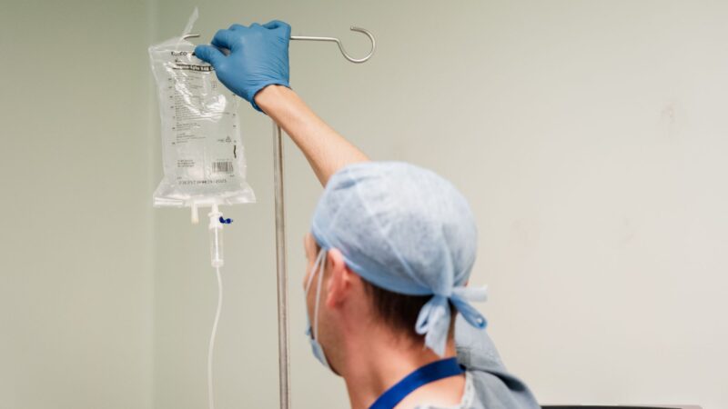 a staff member dressed in scrubs hangs a drip bag